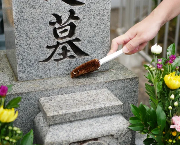 墓石をブラシで清掃している様子
